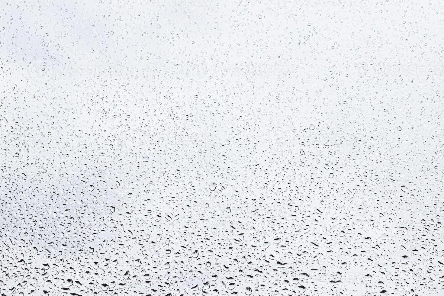 Rain drops on window glasses surface with gray sky background . Natural backdrop of raindrops. Abstract overlay for design. The concept of rainy weather. photo