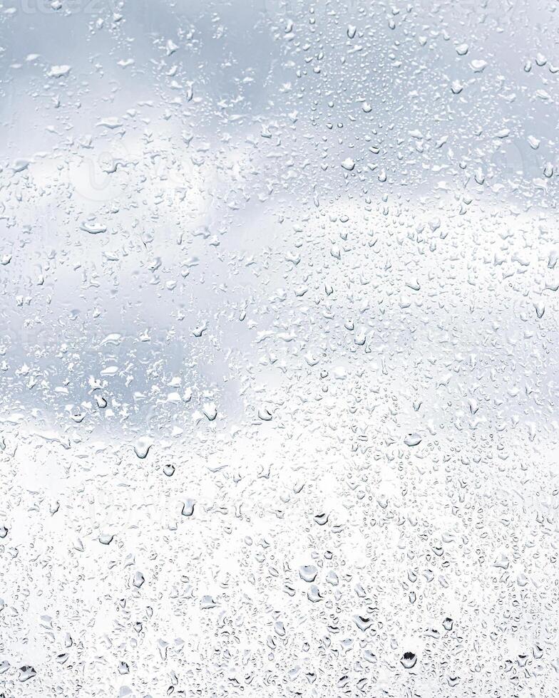 Rain drops on window glasses surface with cloudy sky background . Natural backdrop of raindrops. Abstract overlay for design. The concept of rainy weather. photo