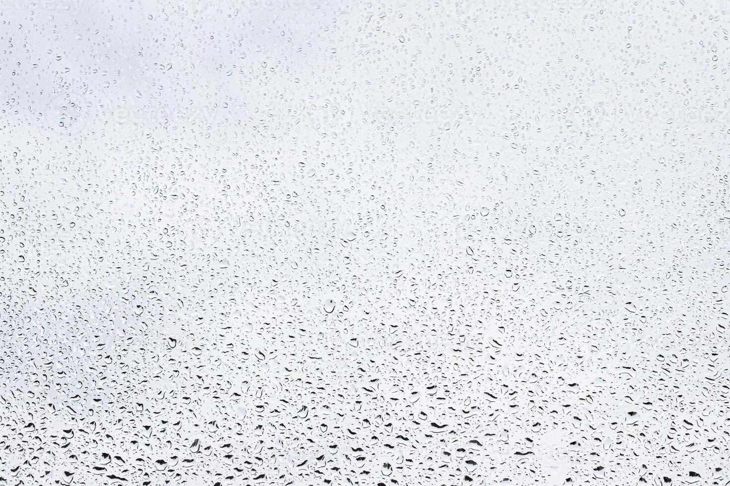 Rain drops on window glasses surface with gray sky background . Natural backdrop of raindrops. Abstract overlay for design. The concept of rainy weather. photo