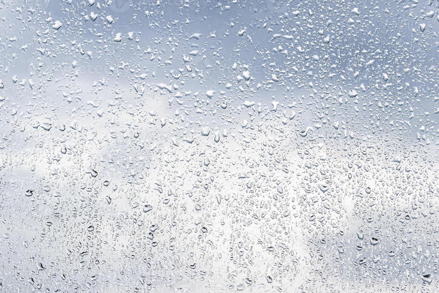 Rain drops on window glasses surface with cloudy background . Natural backdrop of raindrops. Abstract overlay for design. The concept of rainy weather. photo