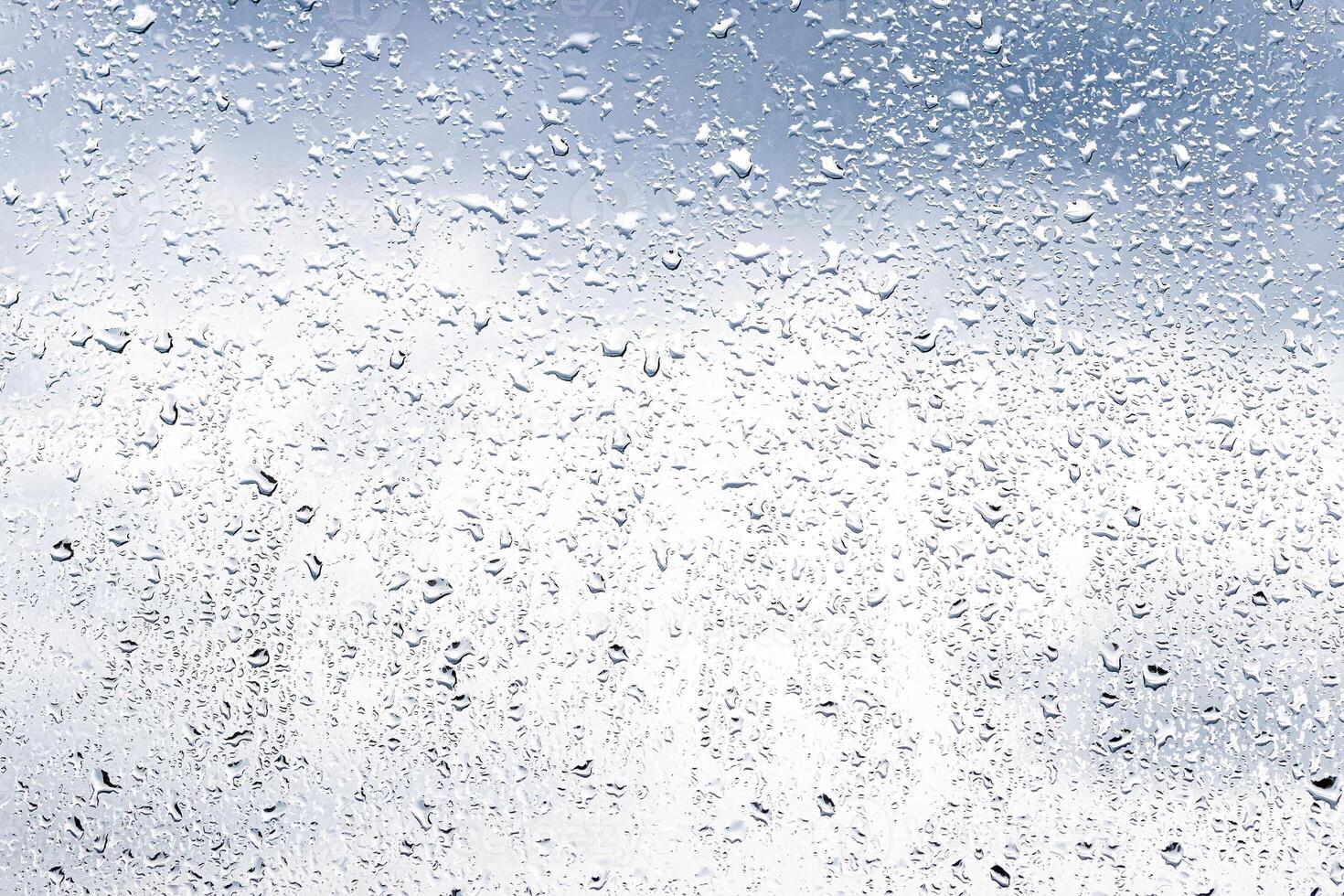 Rain drops on window glasses surface with cloudy sky background . Natural backdrop of raindrops. Abstract overlay for design. The concept of rainy weather. photo