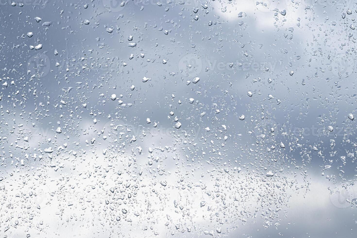 Rain drops on window glasses surface with cloudy background . Natural backdrop of raindrops. Abstract overlay for design. The concept of rainy weather. photo