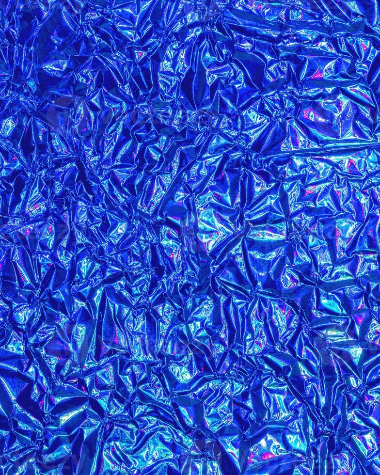 Texture of crumpled aluminum kitchen foil with reflected violet and green light. photo