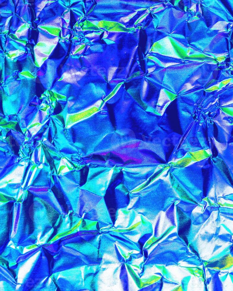 Texture of crumpled aluminum kitchen foil with reflected violet and green light. photo