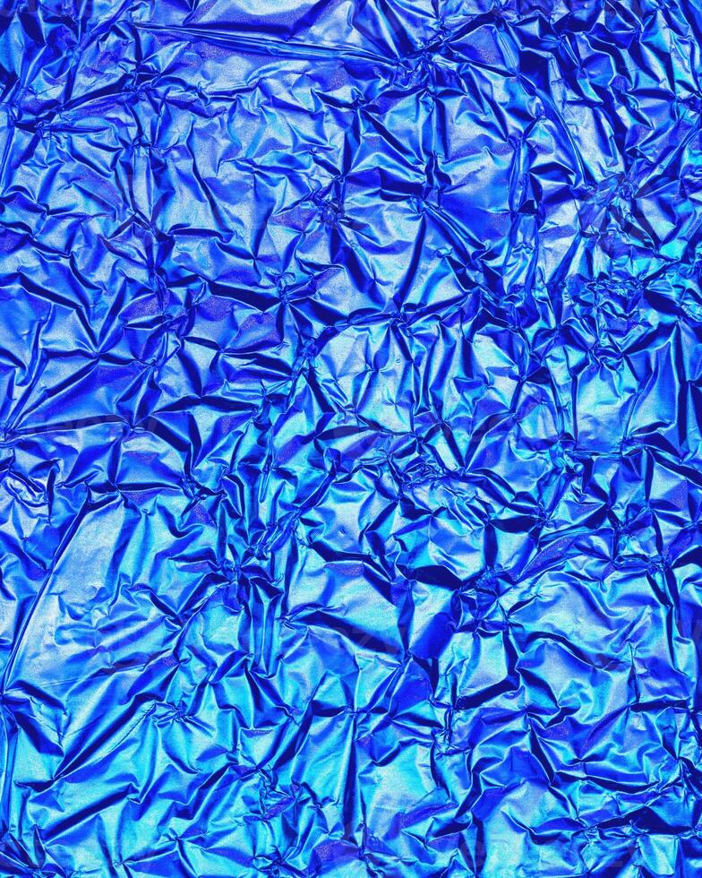 Texture of crumpled aluminum kitchen foil with reflected violet and green light. photo