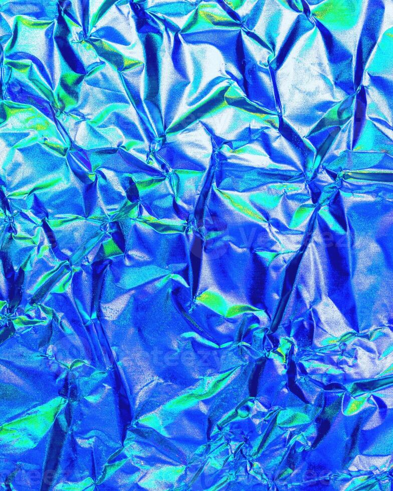 Texture of crumpled aluminum kitchen foil with reflected violet and green light. photo