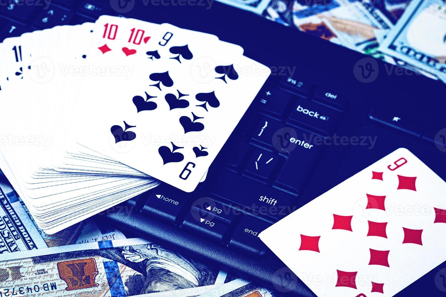 Hundred dollar bills, a deck of playing cards and a black keyboard. Concept of card games, casino or poker online. Online gambling. photo