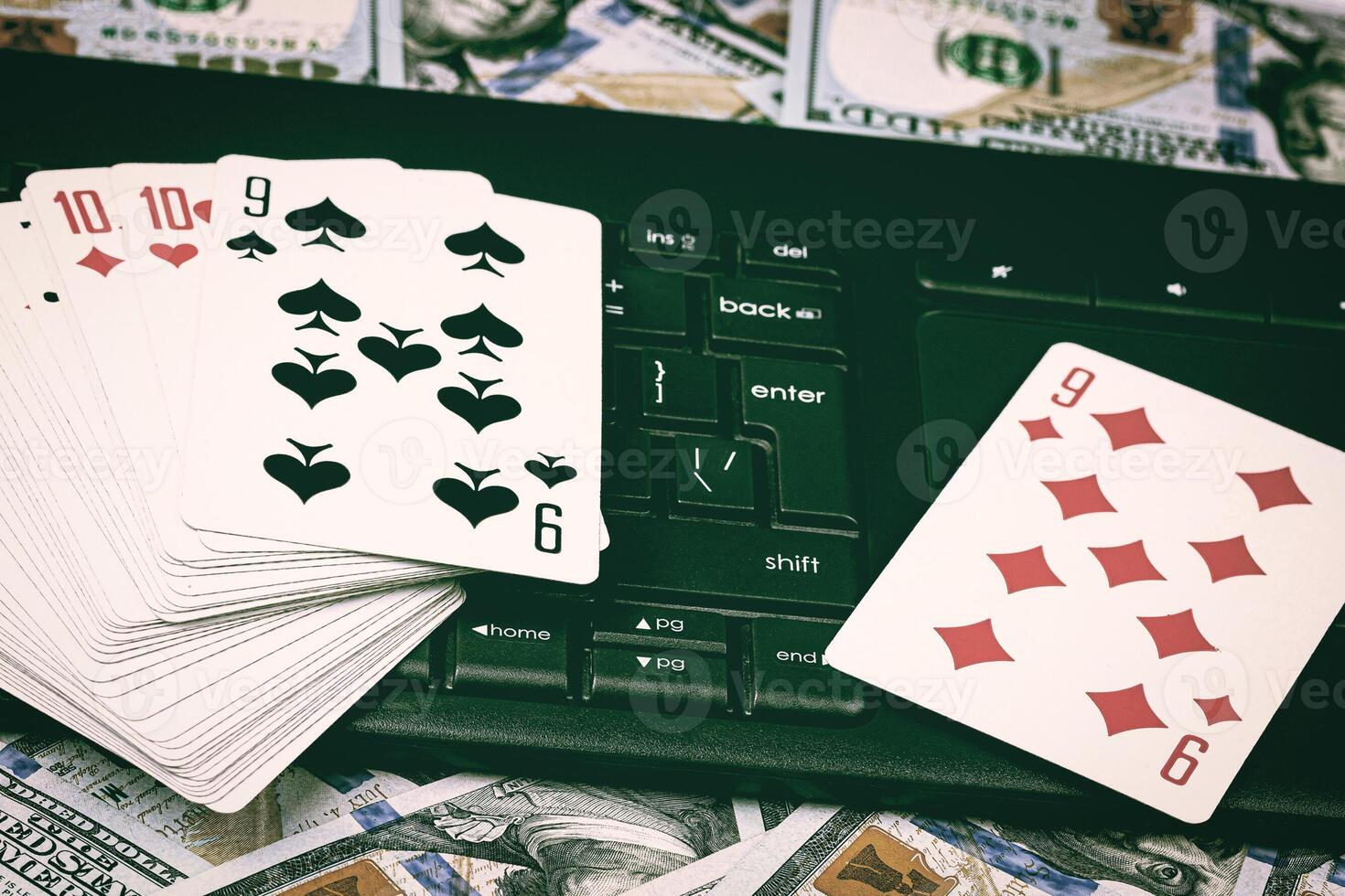 Hundred dollar bills, a deck of playing cards and a black keyboard. Concept of card games, casino or poker online. Online gambling. photo
