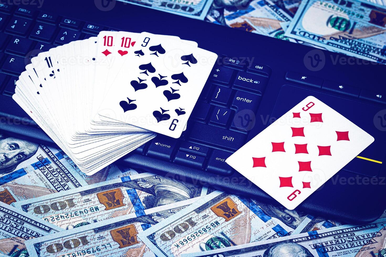 Hundred dollar bills, a deck of playing cards and a black keyboard. Concept of card games, casino or poker online. Online gambling. photo
