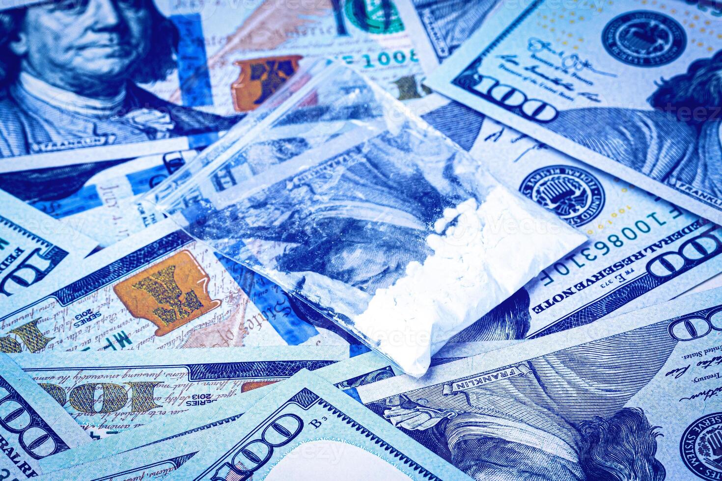 A bag with white narcotic powder like heroin or cocaine on the background of one hundred dollar bills. The concept of the use and sale of drugs. photo