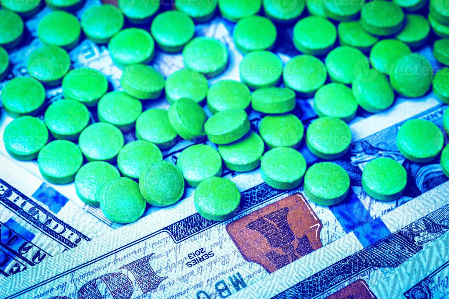 Green pills on the background of one hundred dollar bills. The concept of the expensive cost of healthcare or financing medicine. photo