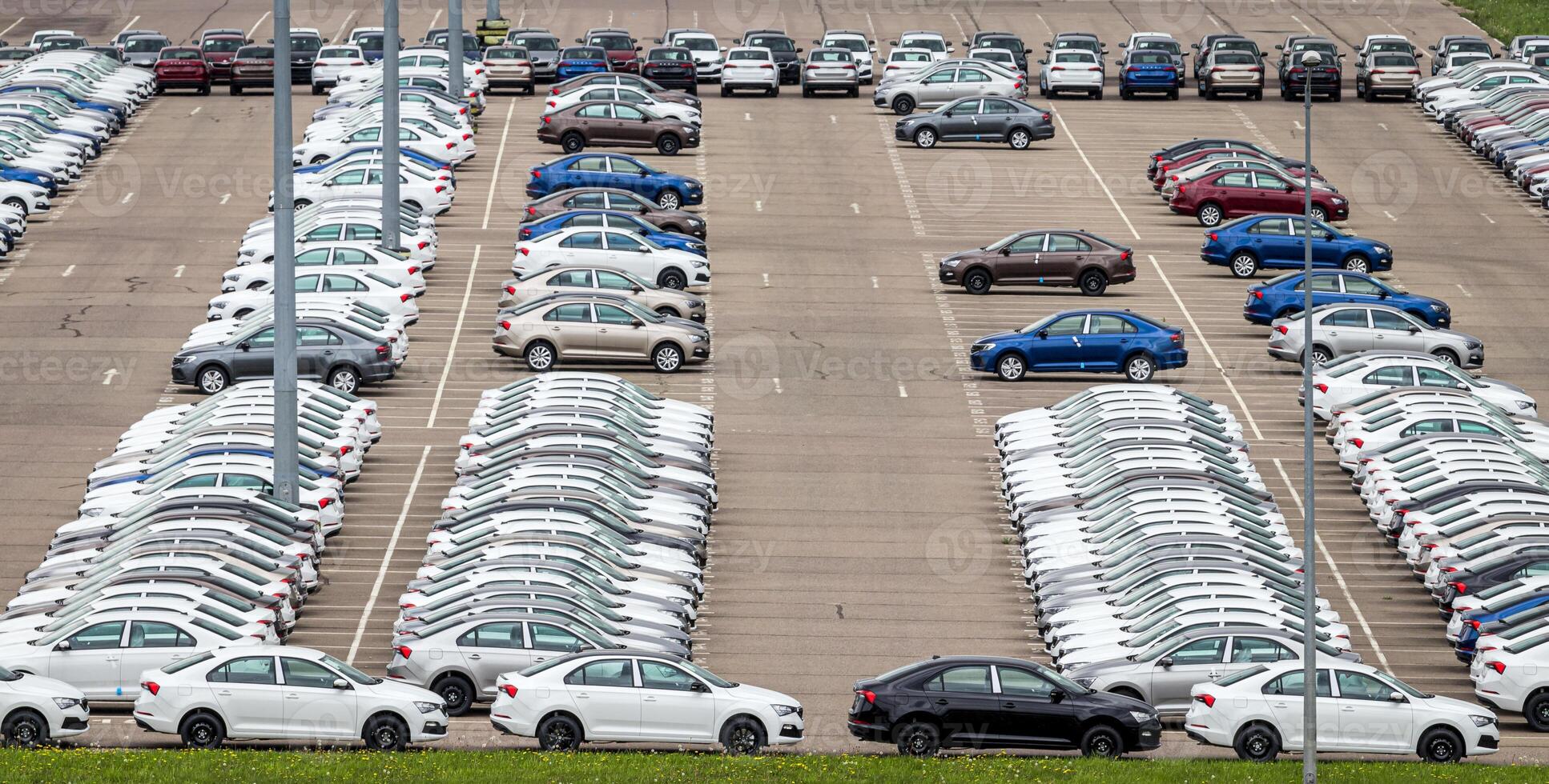 Rows of a new cars parked in a distribution center on a cloudy day in the spring, a car factory. Top view to the parking in the open air. photo