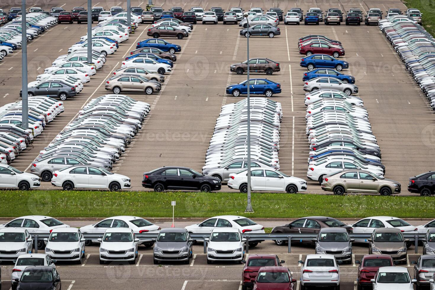 Rows of a new cars parked in a distribution center of a car factory. Top view to the parking in the open air. photo