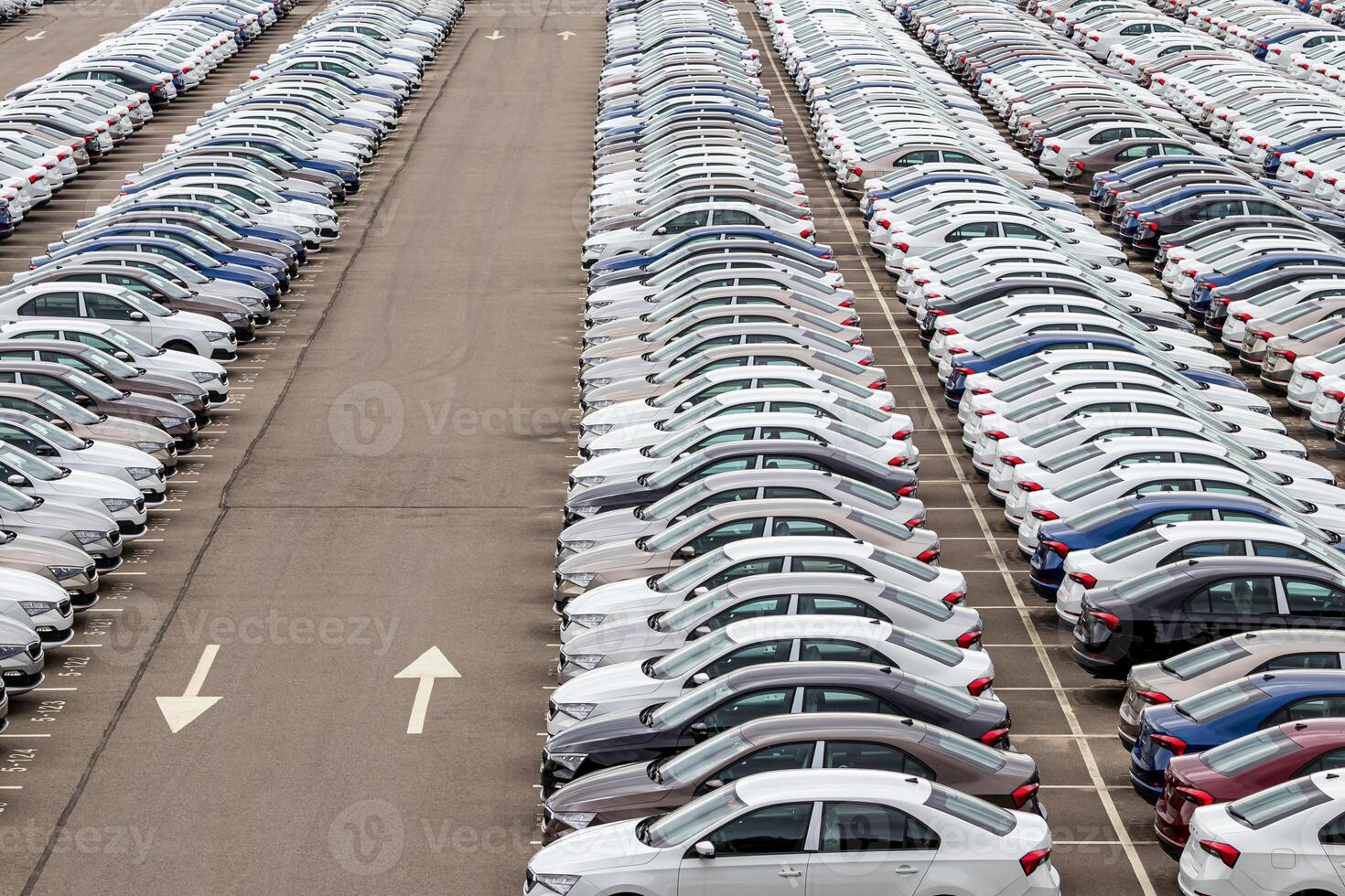 Rows of a new cars parked in a distribution center on a car factory on a cloudy day. Top view to the parking in the open air. photo