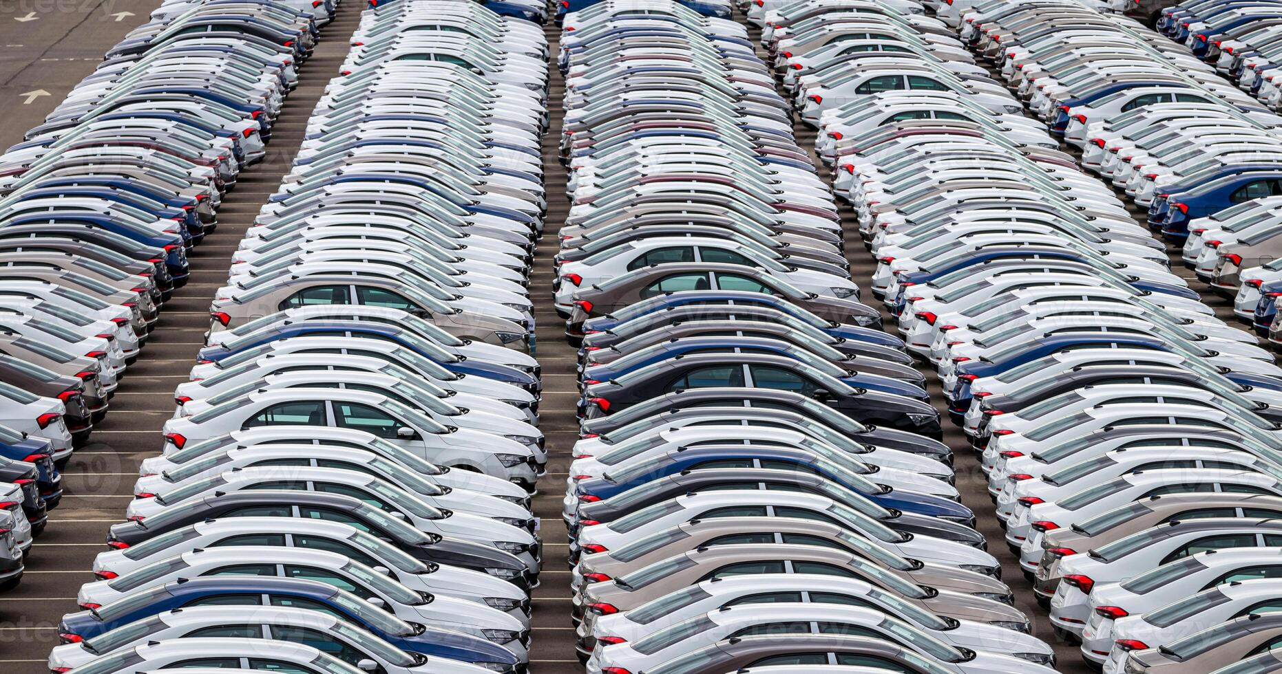 Rows of a new cars parked in a distribution center of a car factory. Top view to the parking in the open air. photo