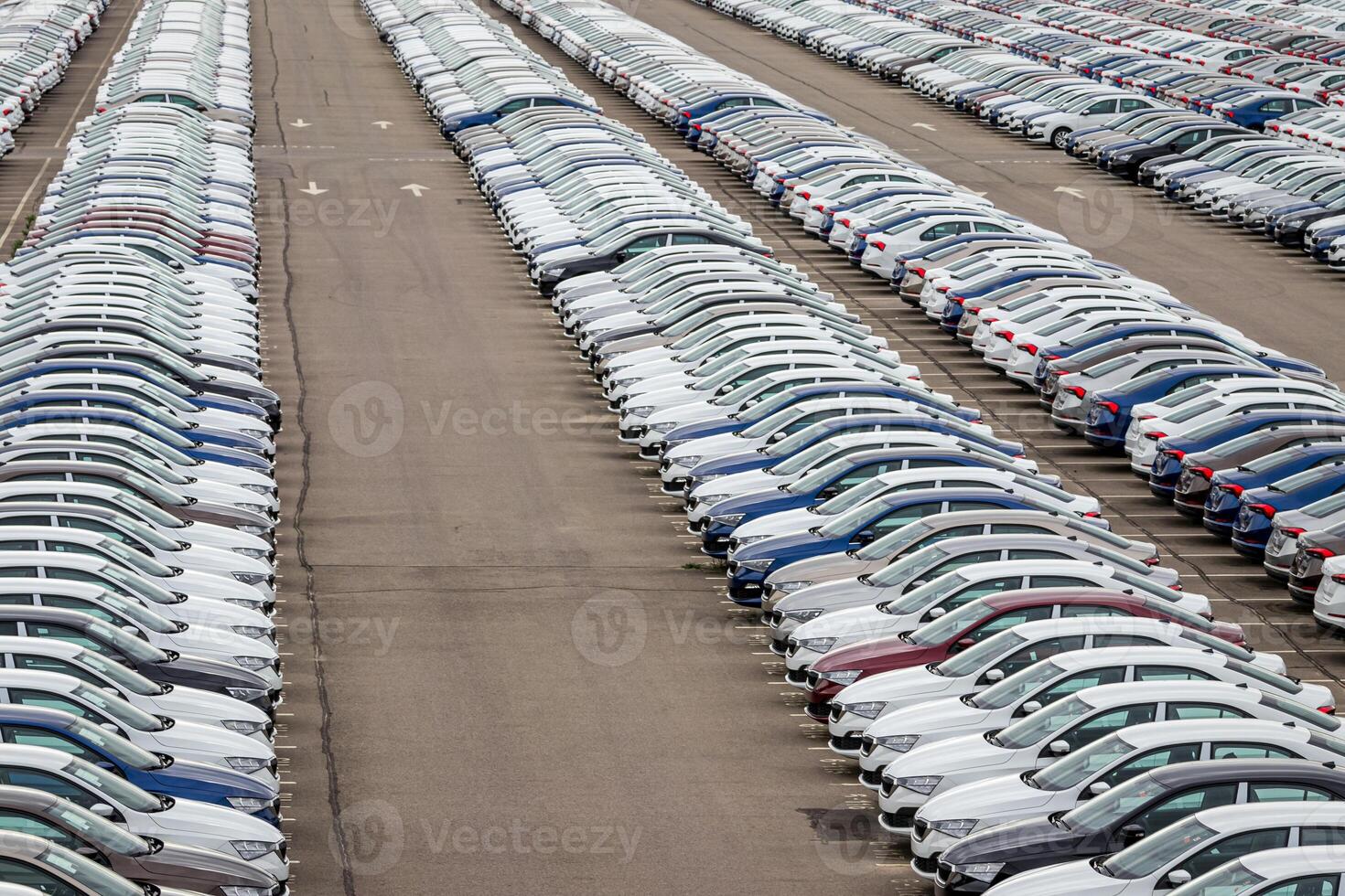 Rows of a new cars parked in a distribution center on a cloudy day in the spring, a car factory. Top view to the parking in the open air. photo