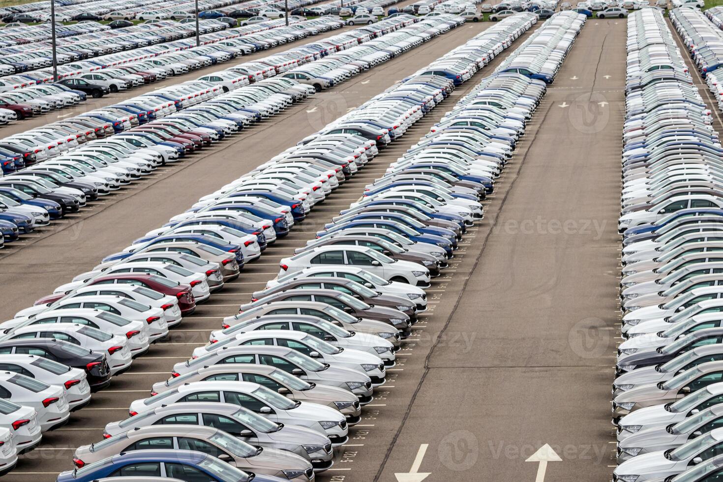 Rows of a new cars parked in a distribution center on a car factory on a cloudy day. Top view to the parking in the open air. photo