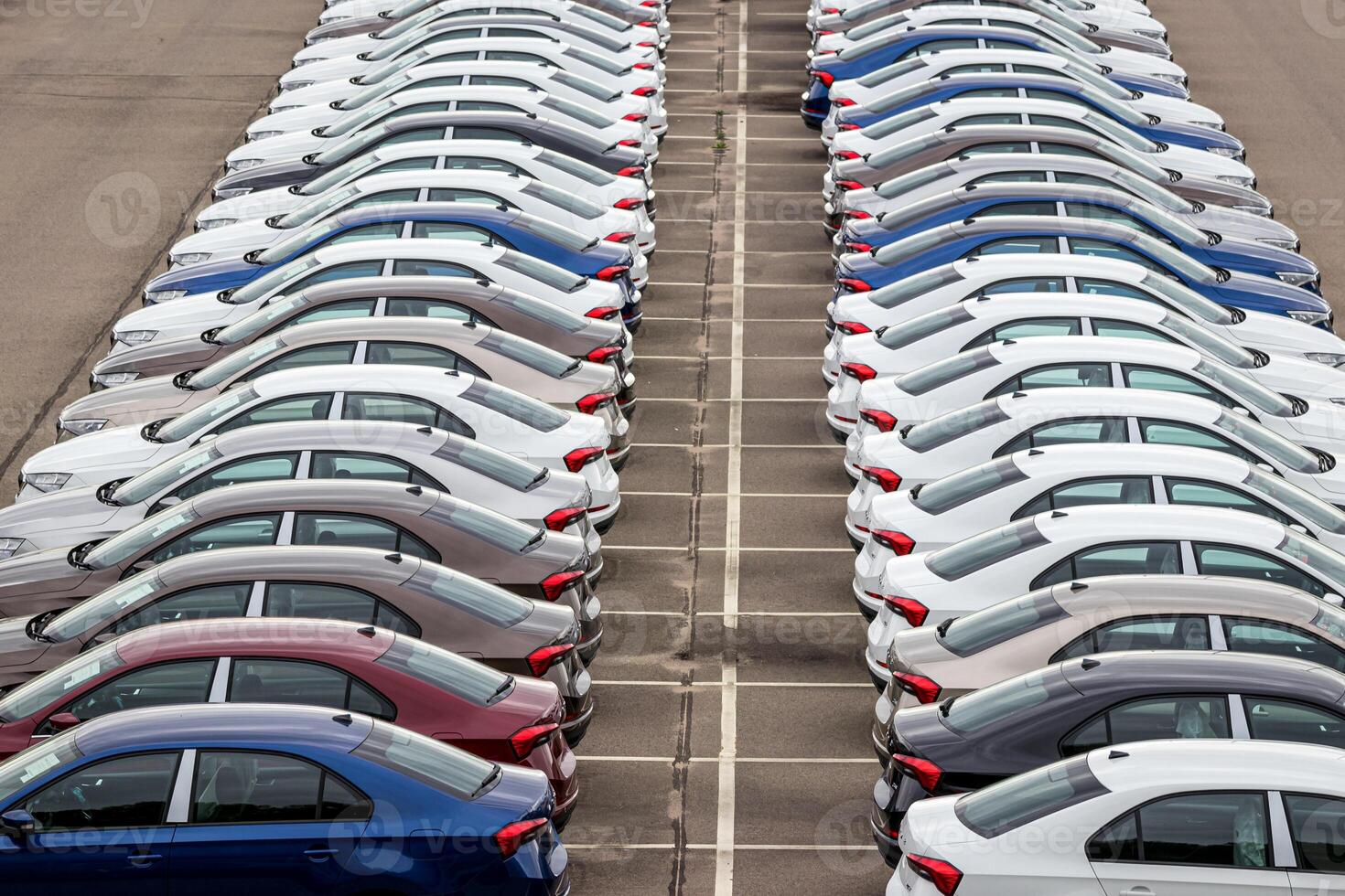 Rows of a new cars parked in a distribution center of a car factory. Top view to the parking in the open air. photo