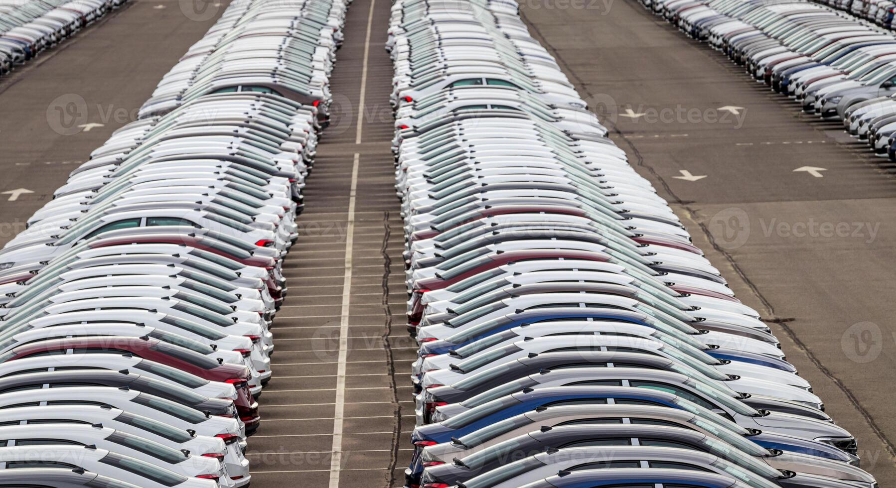 Rows of a new cars parked in a distribution center of a car factory. Top view to the parking in the open air. photo