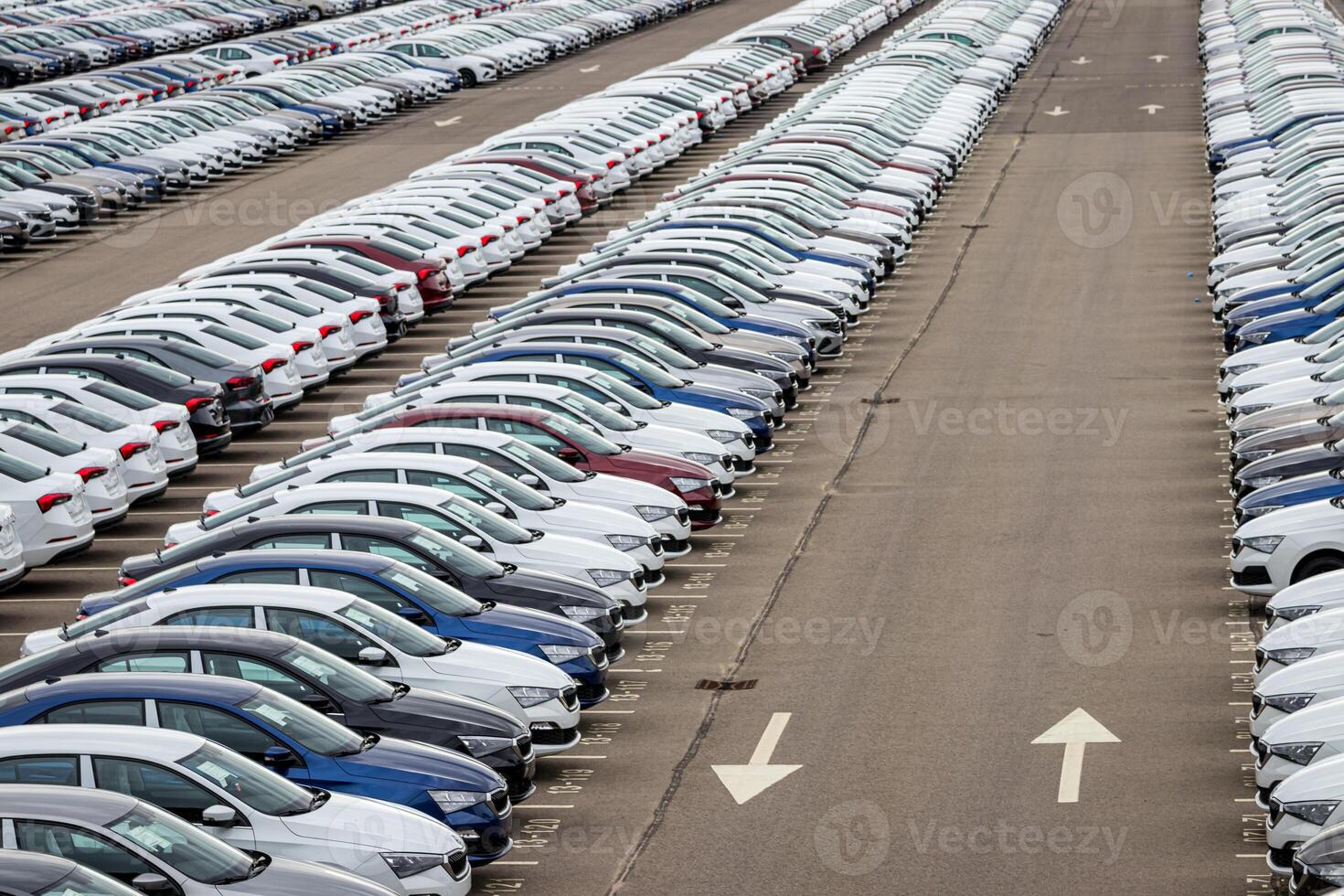 Rows of a new cars parked in a distribution center on a cloudy day in the spring, a car factory. Top view to the parking in the open air. photo
