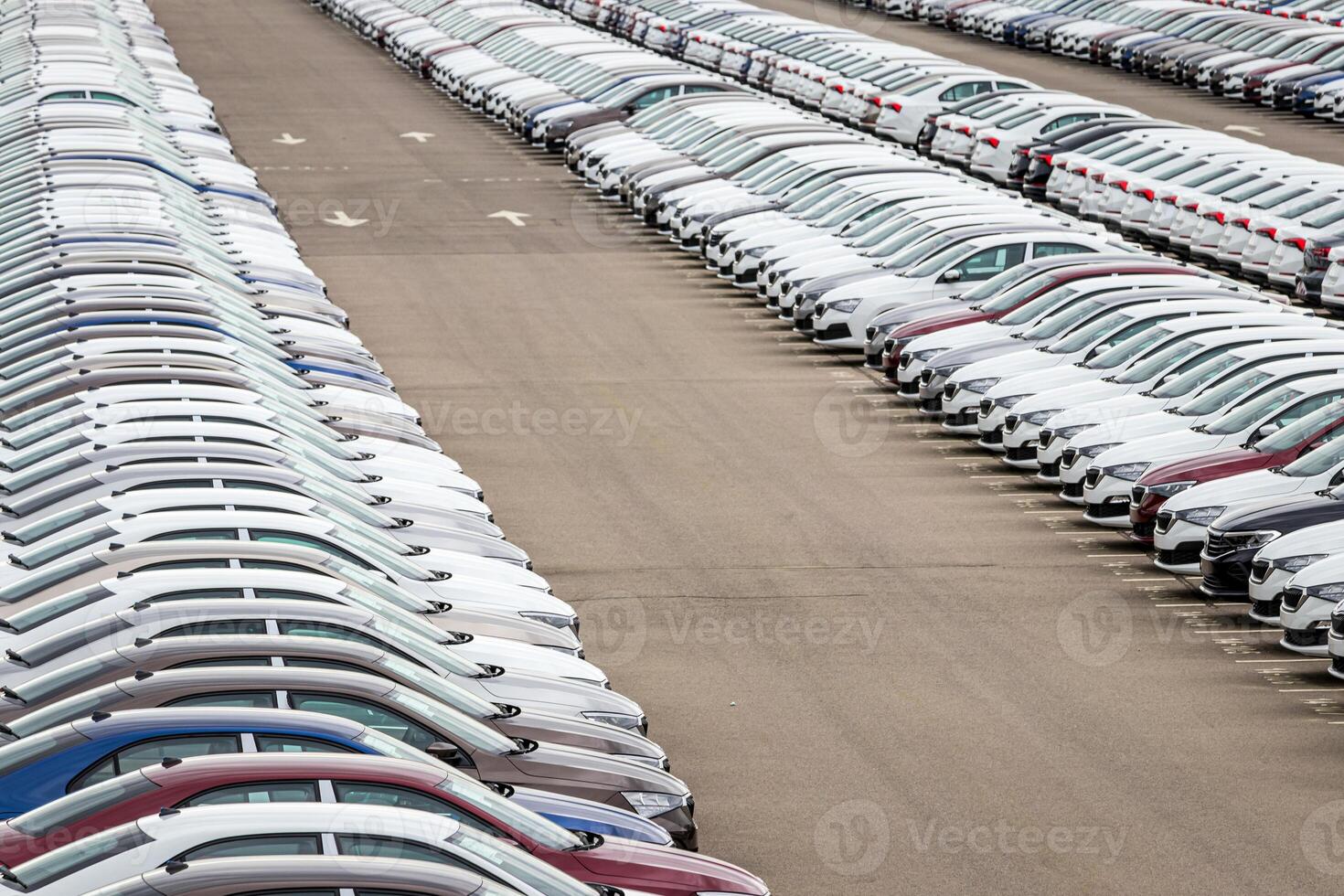Rows of a new cars parked in a distribution center on a cloudy day in the spring, a car factory. Top view to the parking in the open air. photo
