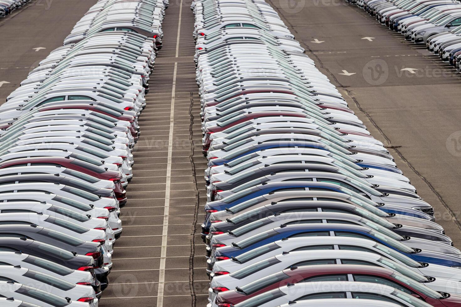 Rows of a new cars parked in a distribution center on a car factory on a cloudy day. Top view to the parking in the open air. photo