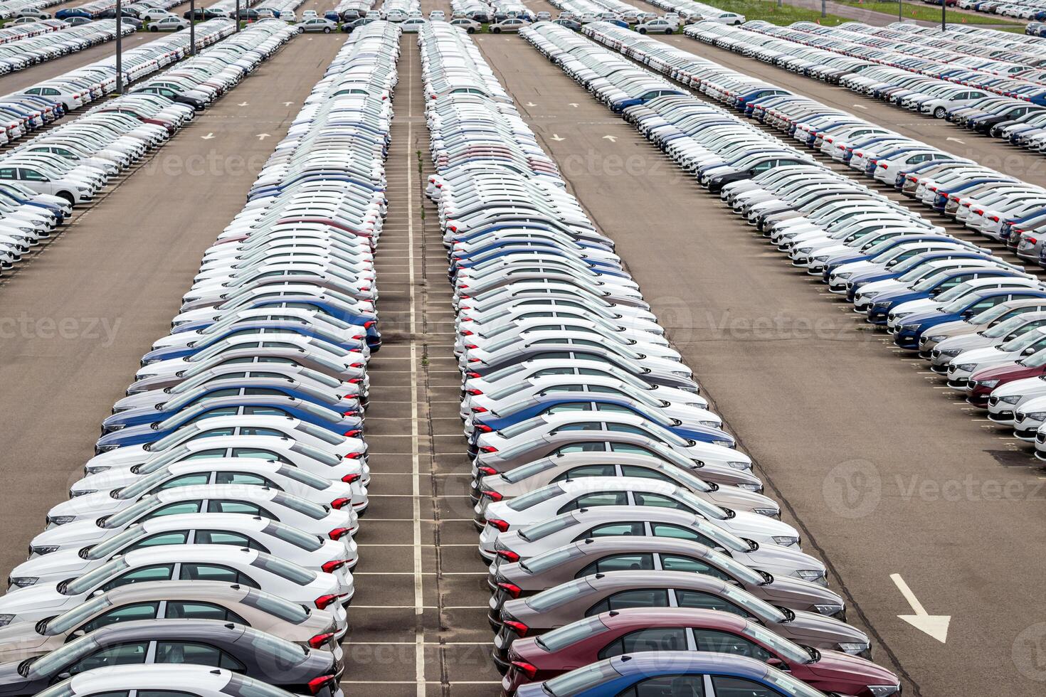 Rows of a new cars parked in a distribution center on a car factory on a cloudy day. Top view to the parking in the open air. photo