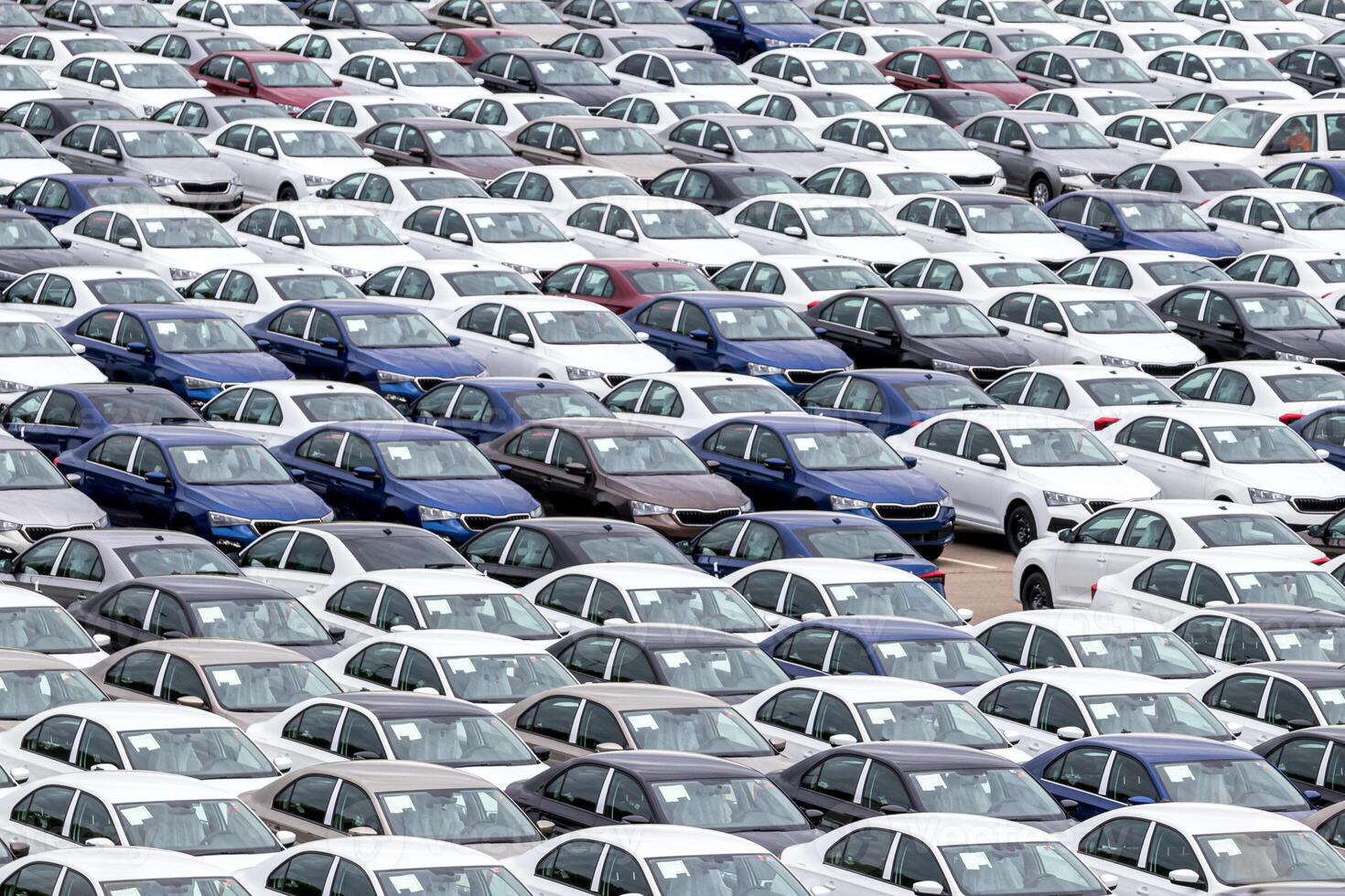 Rows of a new cars parked in a distribution center of a car factory. Top view to the parking in the open air. photo