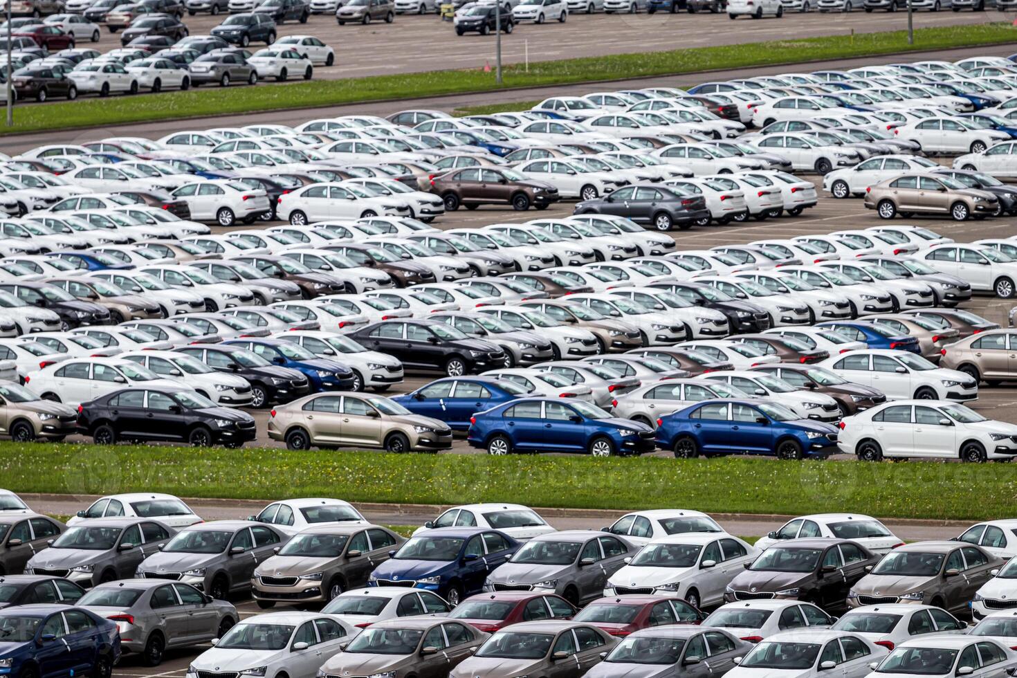 Volkswagen Group Rus, Russia, Kaluga - MAY 24, 2020 Rows of a new cars parked in a distribution center on a cloudy day in the spring, a car factory. Top view to the parking in the open air. photo
