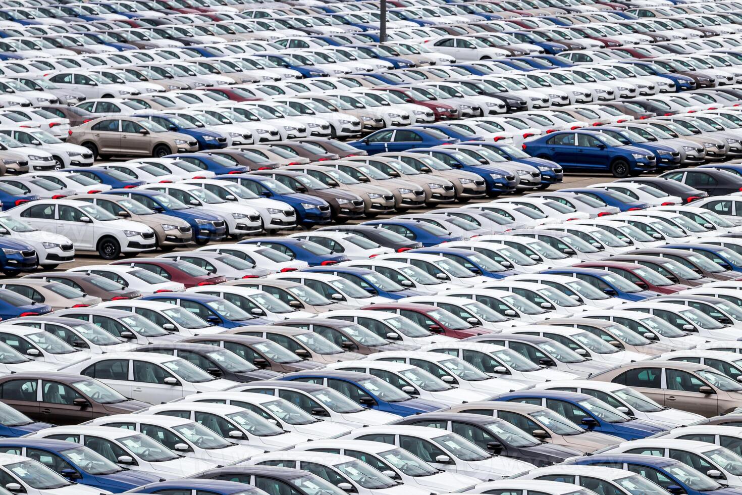 Rows of a new cars parked in a distribution center on a cloudy day in the spring, a car factory. Top view to the parking in the open air. photo