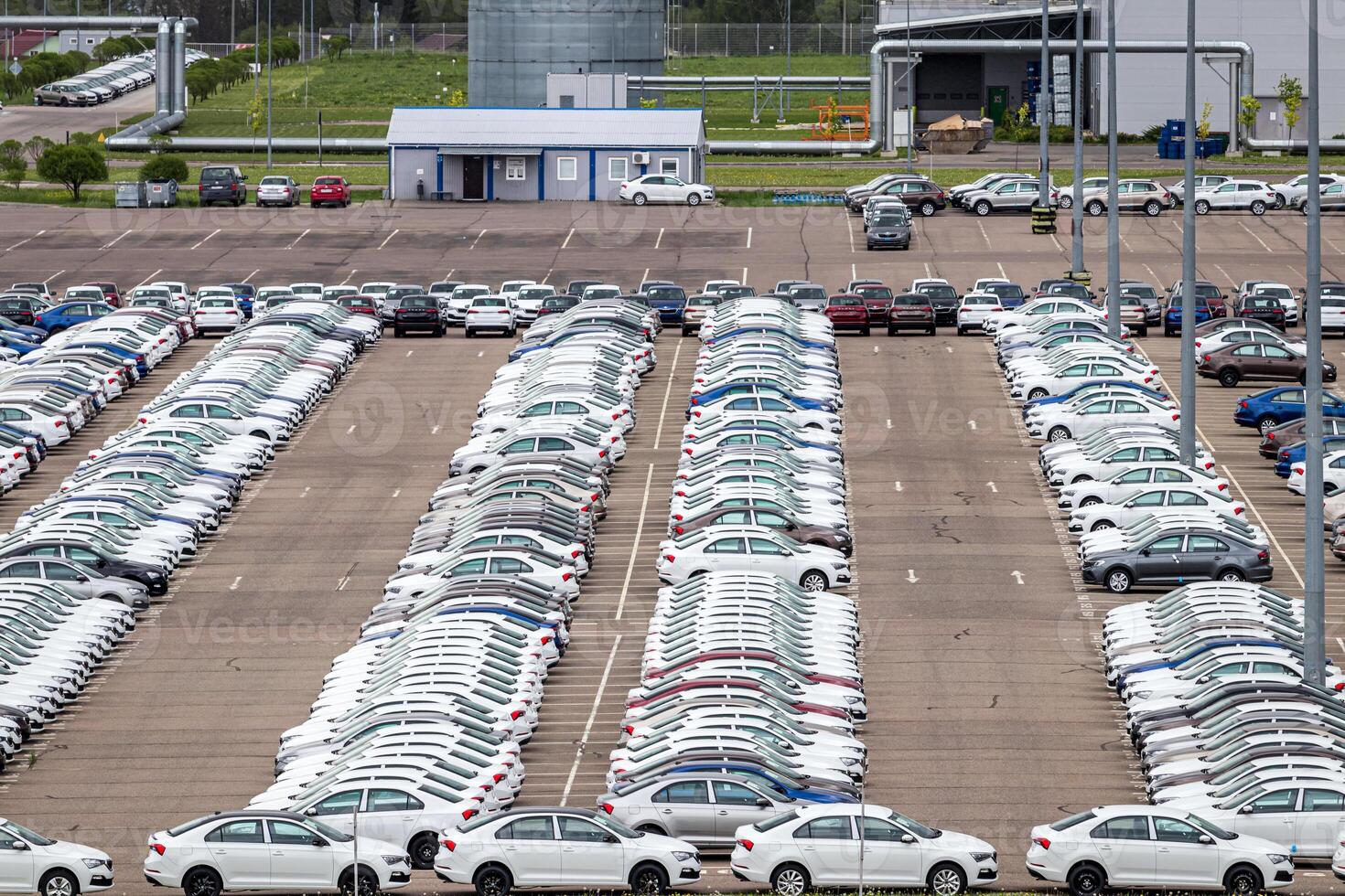 Volkswagen Group Rus, Russia, Kaluga - MAY 24, 2020 Rows of a new cars parked in a distribution center on a cloudy day in the spring and a car factory buildings. Parking in the open air. photo