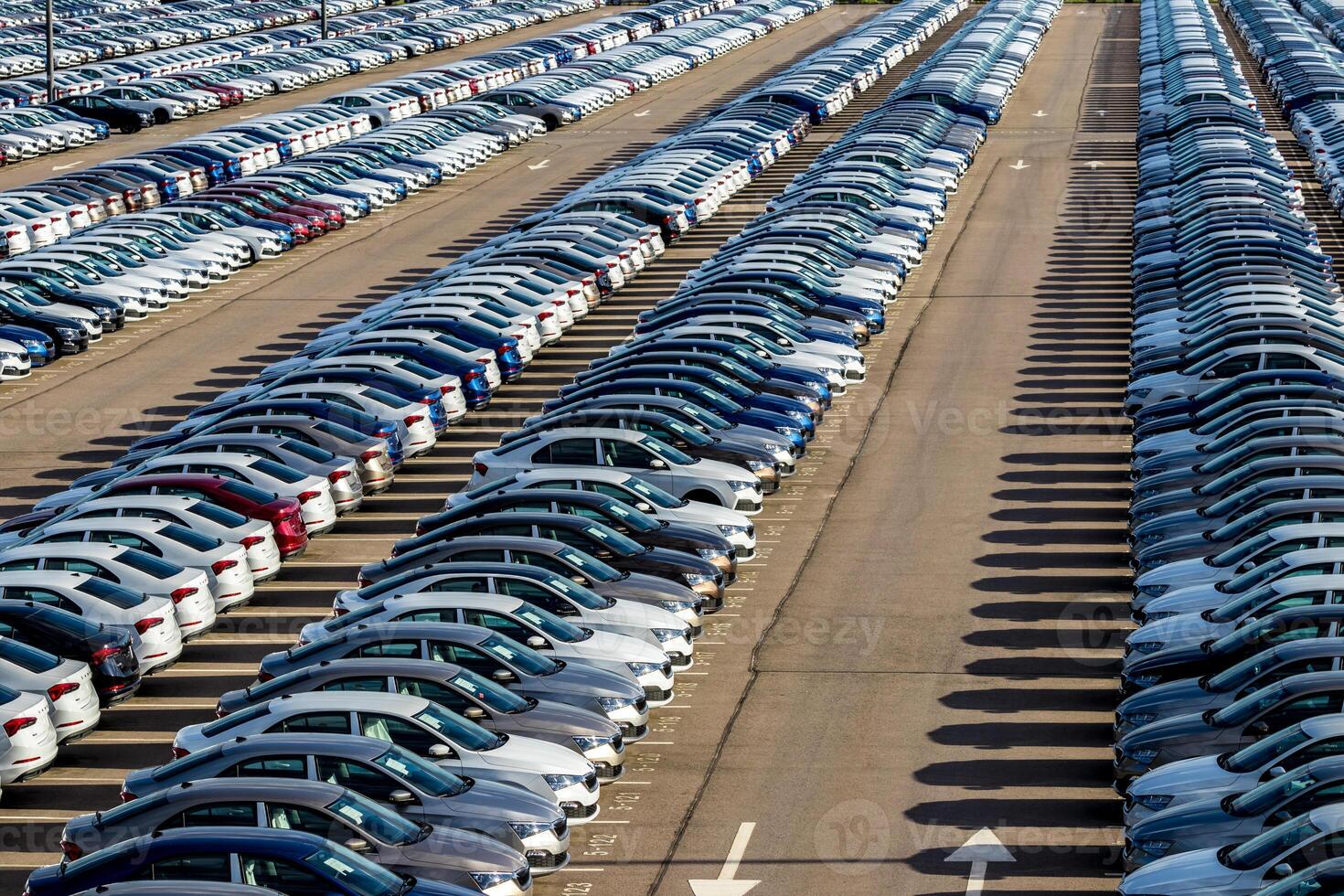 Rows of a new cars parked in a distribution center on a car factory on a sunny day. Top view to the parking in the open air. photo