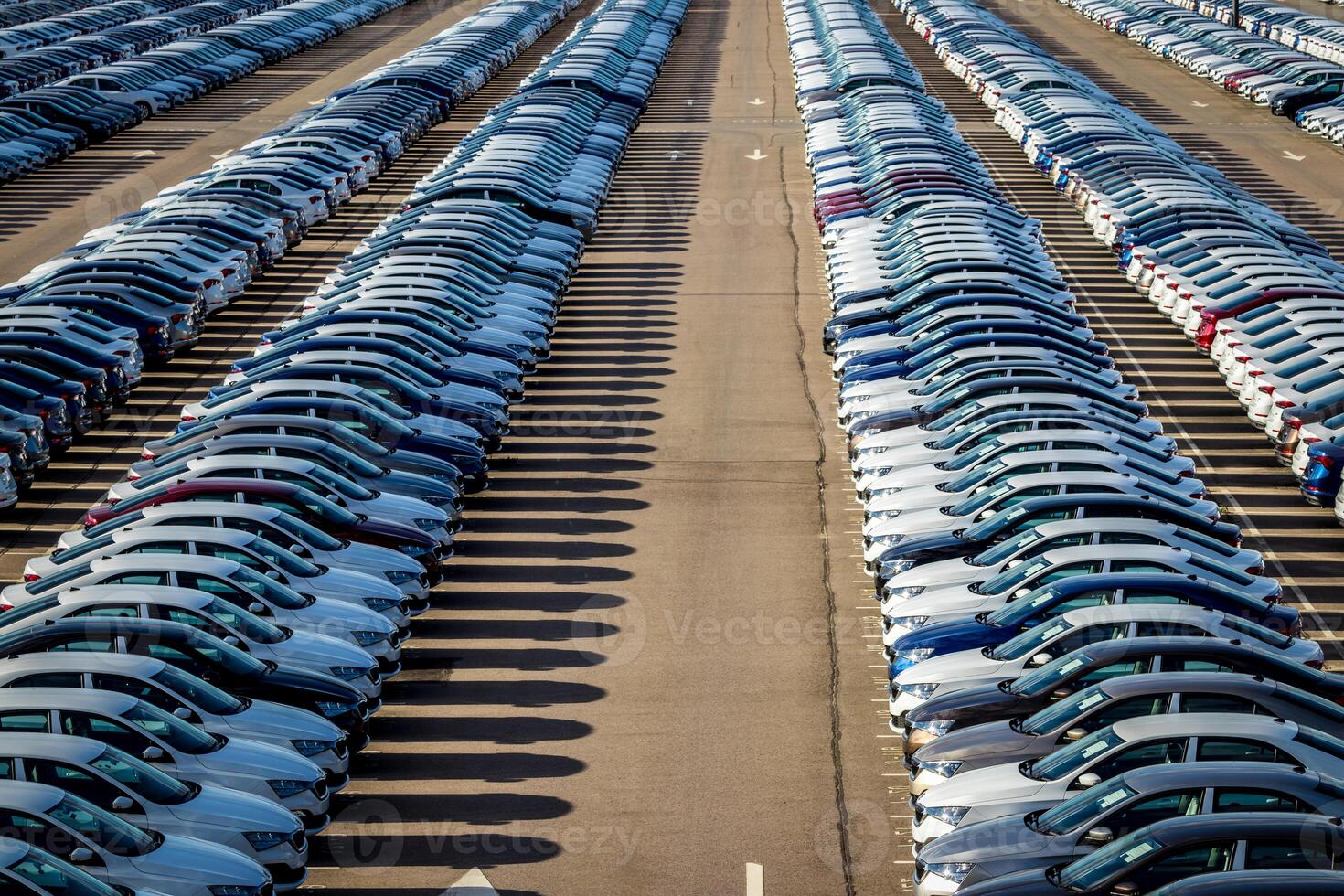 Rows of a new cars parked in a distribution center on a car factory on a sunny day. Parking in the open air. photo