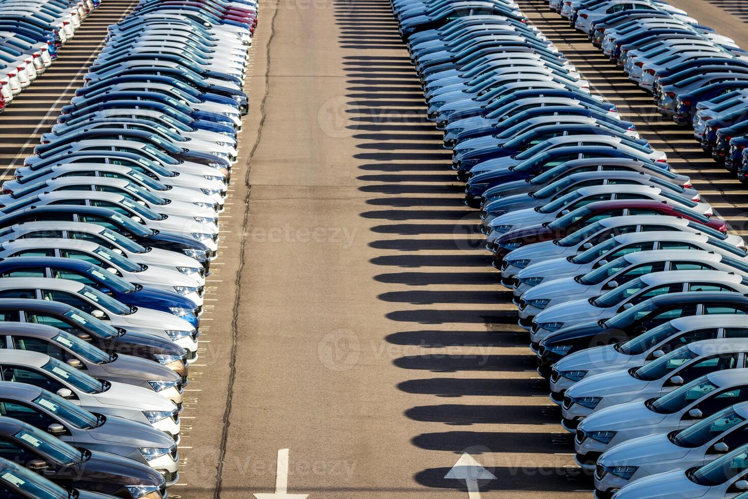 Rows of a new cars parked in a distribution center on a car factory on a sunny day. Top view to the parking in the open air. photo