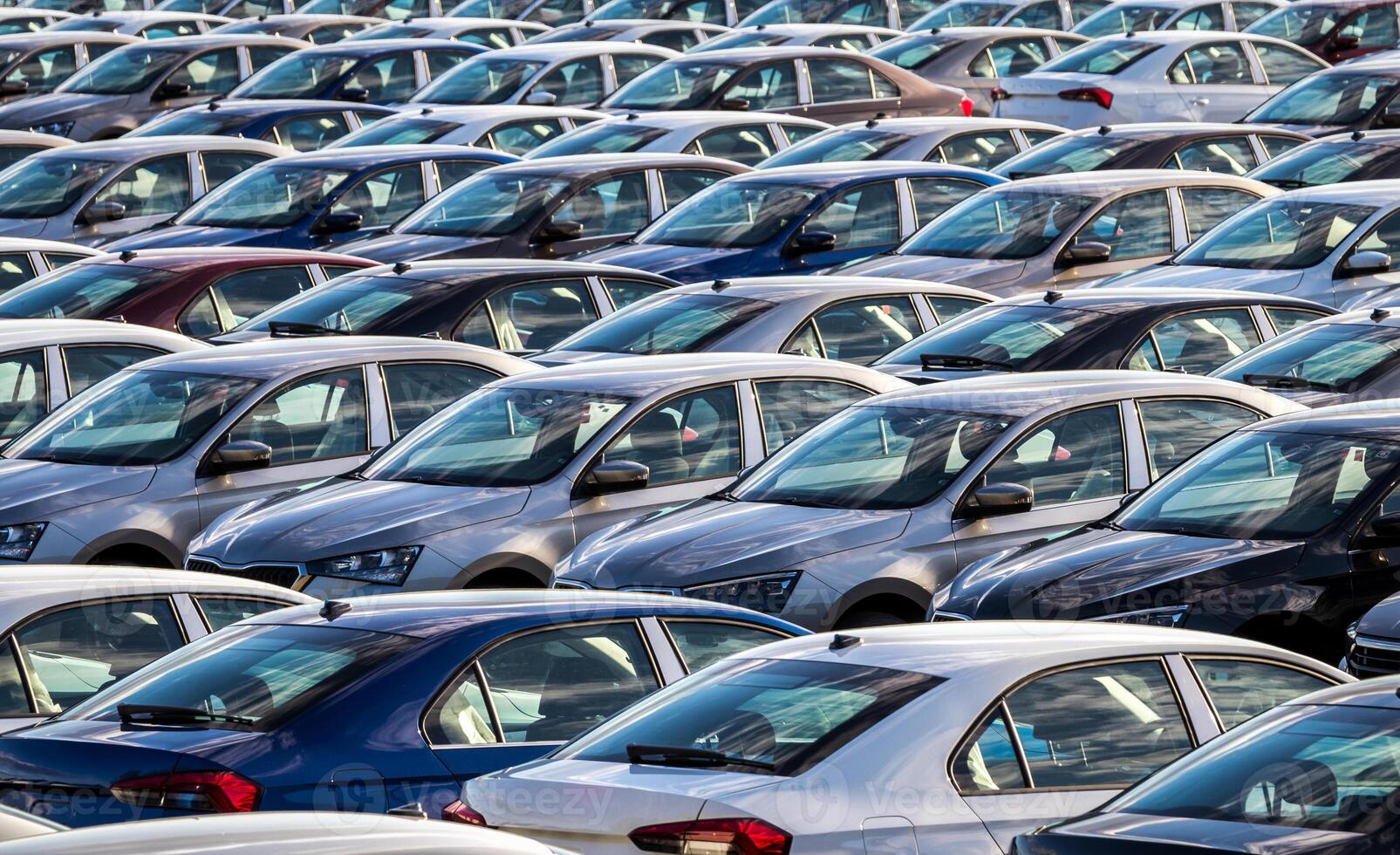 Rows of a new cars parked in a distribution center on a car factory on a sunny day. Parking in the open air. photo