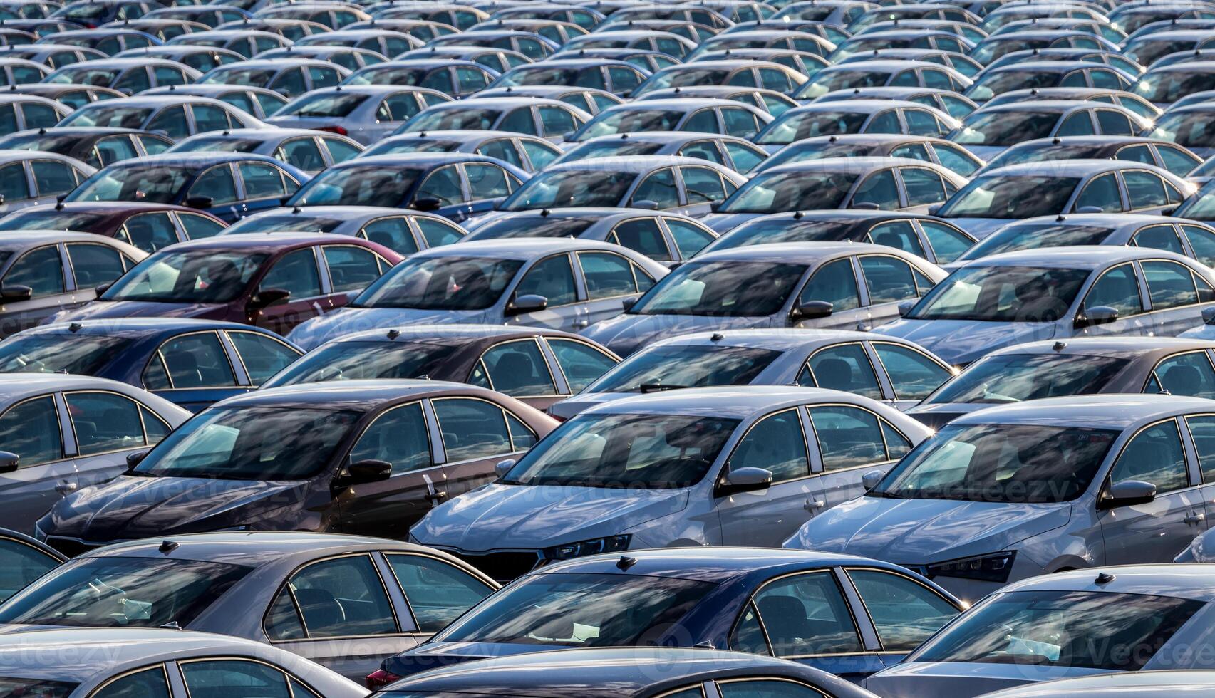 Rows of a new cars parked in a distribution center on a car factory on a sunny day. Top view to the parking in the open air. photo