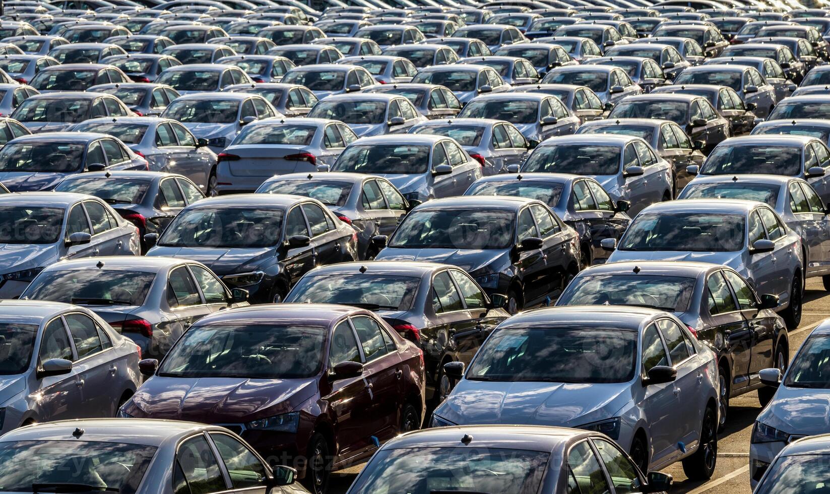 Rows of a new cars parked in a distribution center on a car factory on a sunny day. Top view to the parking in the open air. photo