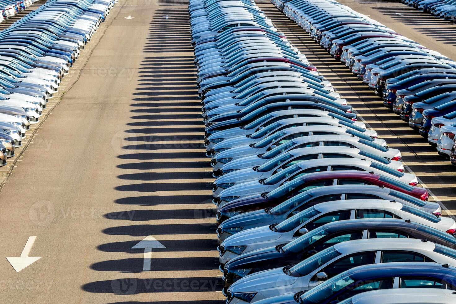 Rows of a new cars parked in a distribution center on a car factory on a sunny day. Top view to the parking in the open air. photo