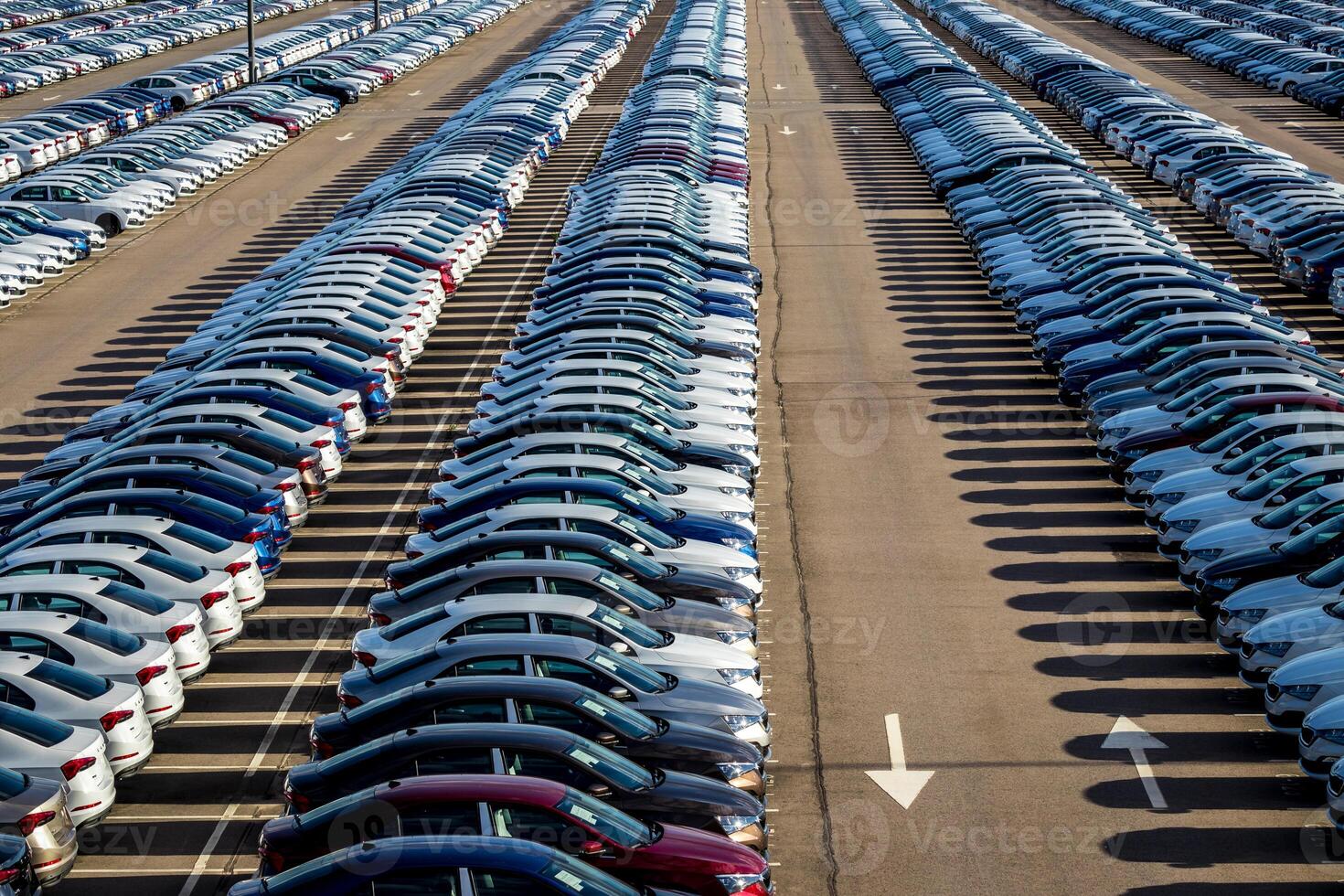 Rows of a new cars parked in a distribution center on a car factory on a sunny day. Top view to the parking in the open air. photo