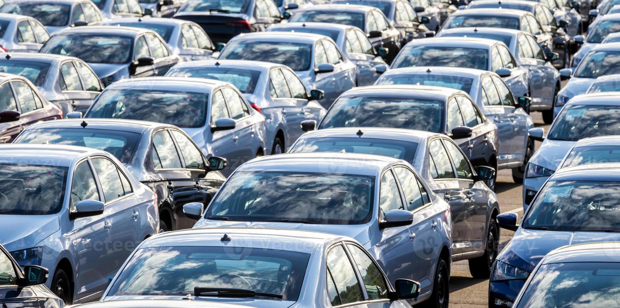 Rows of a new cars parked in a distribution center on a car factory on a sunny day. Top view to the parking in the open air. photo