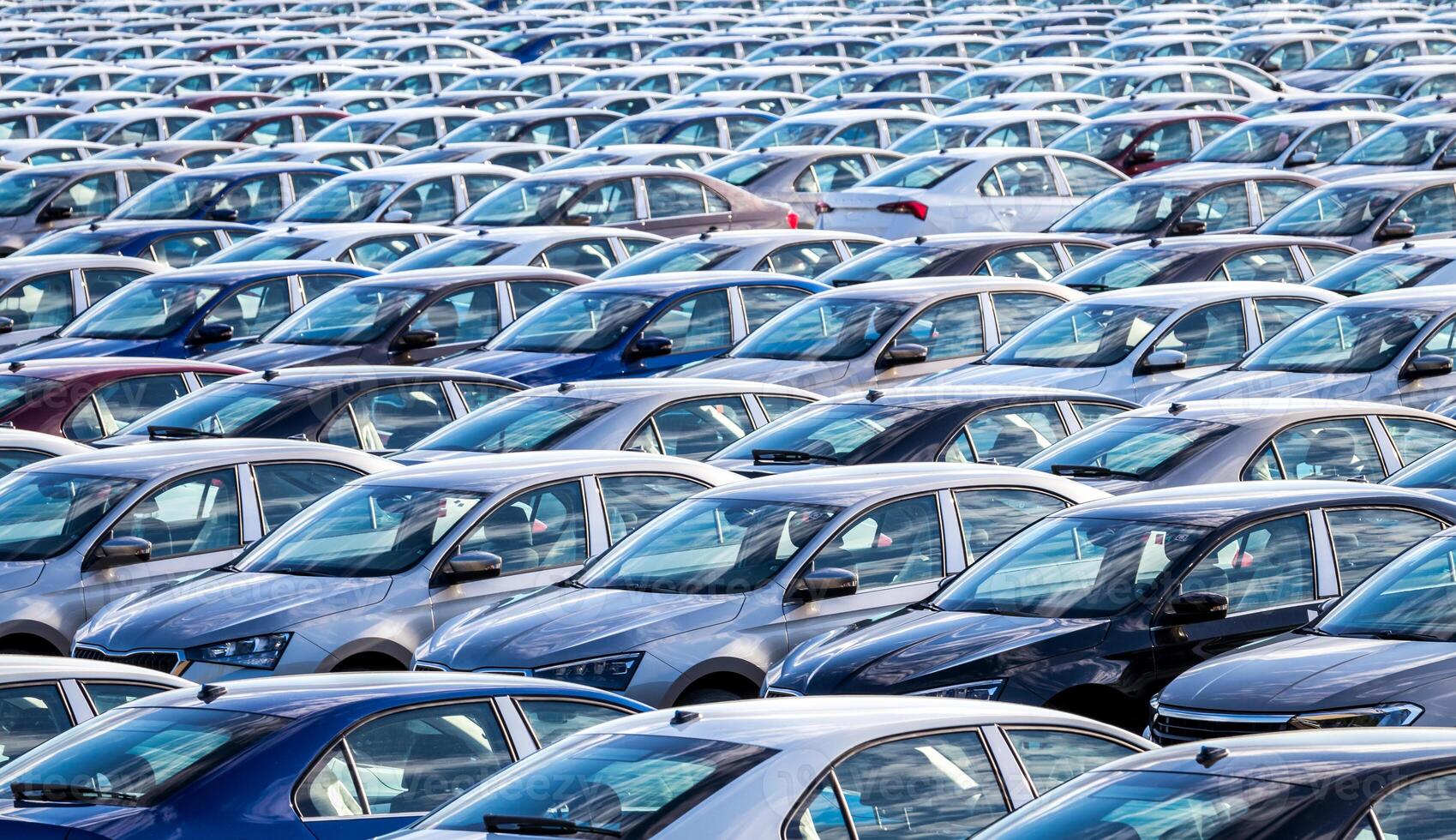 Rows of a new cars parked in a distribution center on a car factory on a sunny day. Top view to the parking in the open air. photo