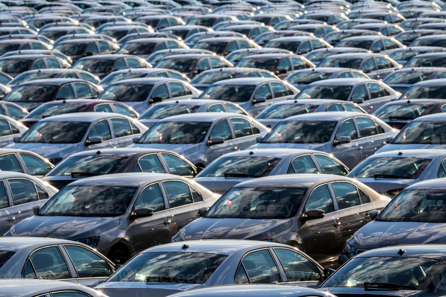 Rows of a new cars parked in a distribution center on a car factory on a sunny day. Top view to the parking in the open air. photo