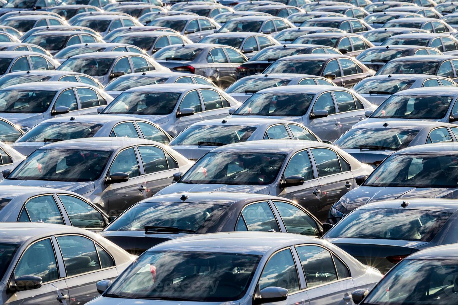 Rows of a new cars parked in a distribution center on a car factory on a sunny day. Top view to the parking in the open air. photo