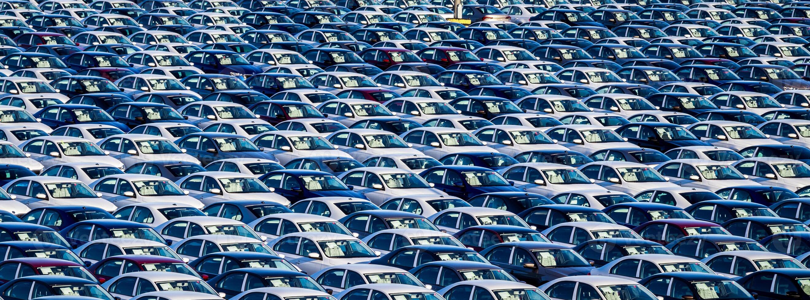 Rows of a new cars parked in a distribution center on a car factory on a sunny day. Parking in the open air. photo