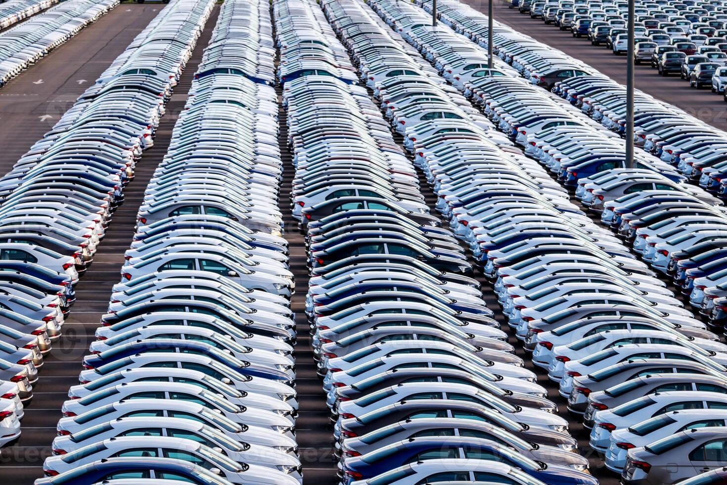 Rows of a new cars parked in a distribution center on a car factory on a sunny day. Parking in the open air. photo