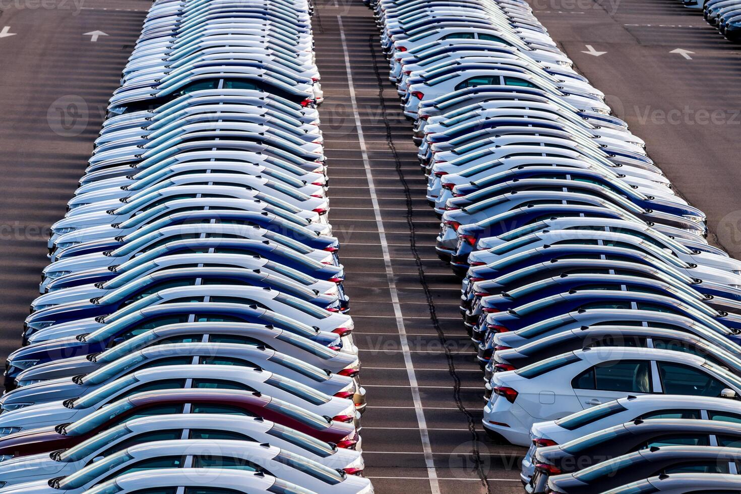 Rows of a new cars parked in a distribution center on a car factory on a sunny day. Top view to the parking in the open air. photo