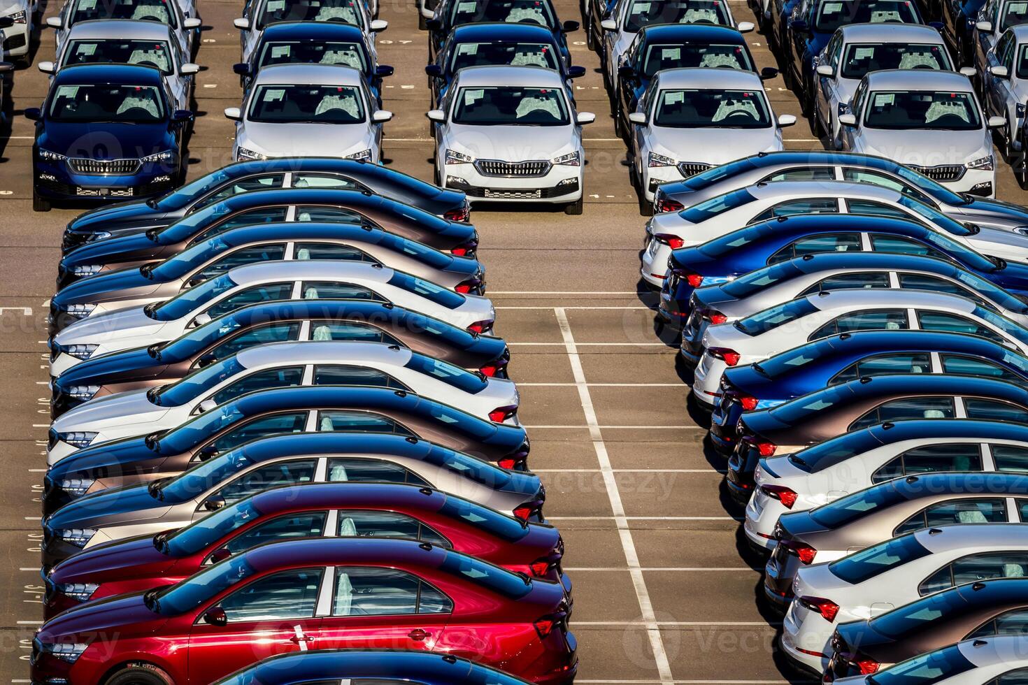 Rows of a new cars parked in a distribution center on a car factory on a sunny day. Top view to the parking in the open air. photo