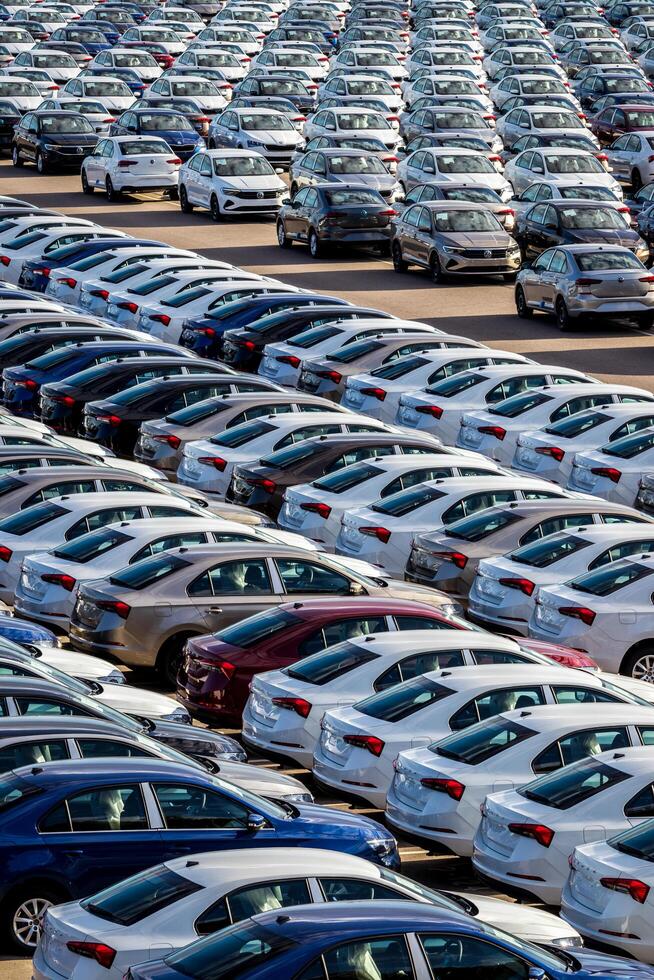 Volkswagen Group Rus, Russia, Kaluga - MAY 25, 2020 Rows of a new cars parked in a distribution center on a sunny day in the spring. Top view to a parking in the open air. photo