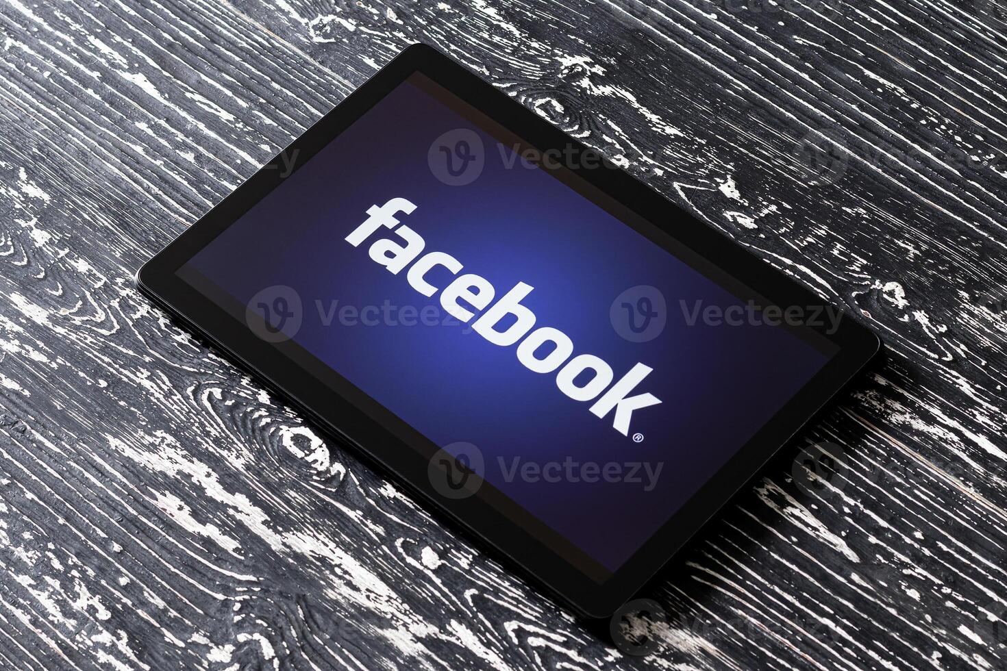 Tablet computer on a black wooden table with a social network facebook logo. photo