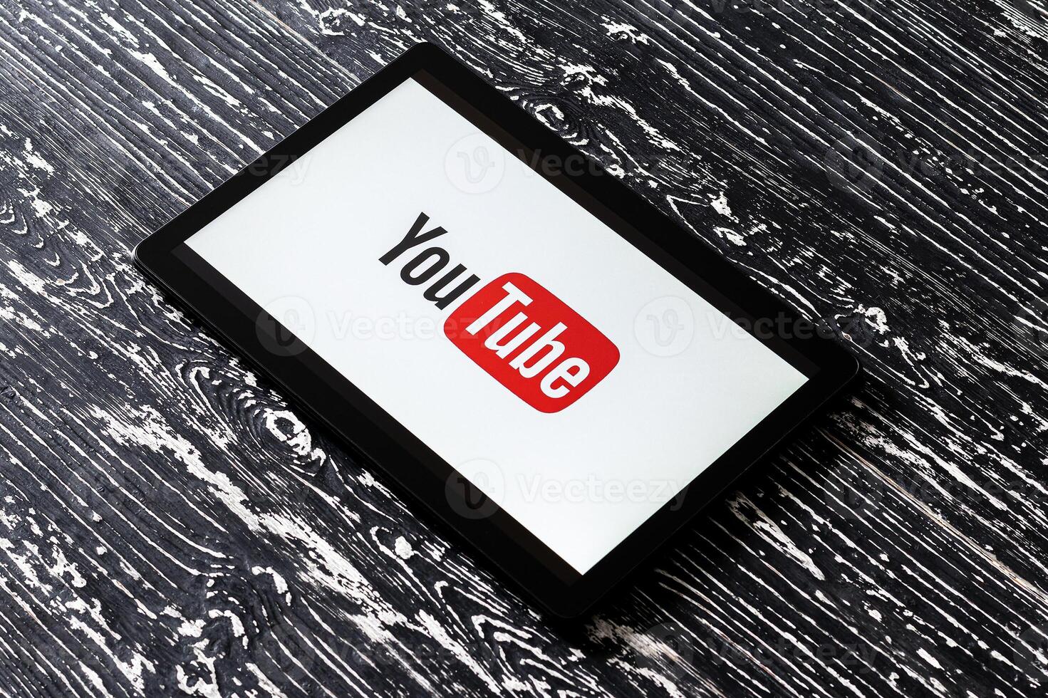 Tablet computer on a black wooden table with a social network YouTube logo on the screen. photo